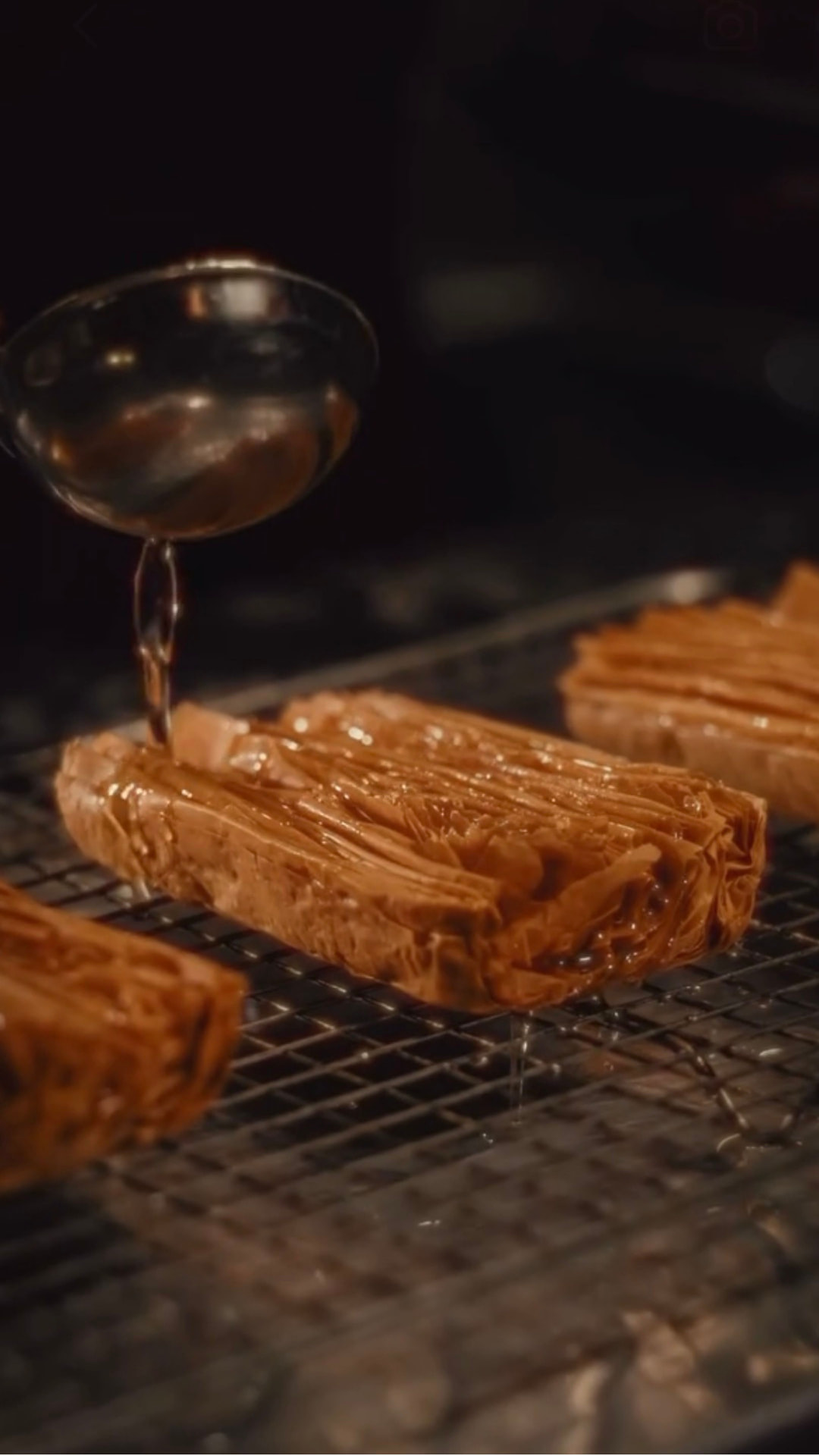 Syrup poured over baklava on a cooling rack