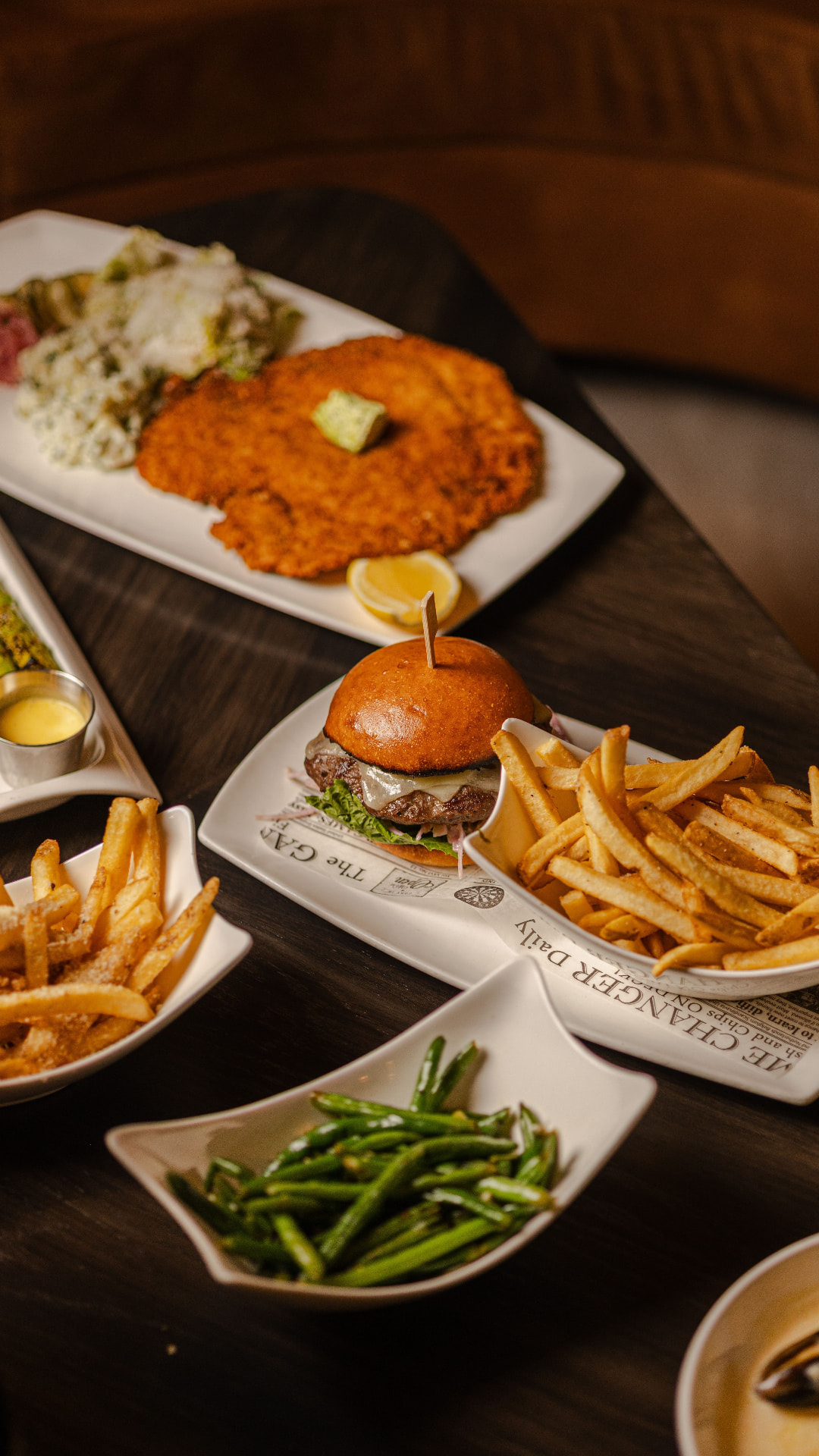 Schnitzel, slider and fries spread on a dark table