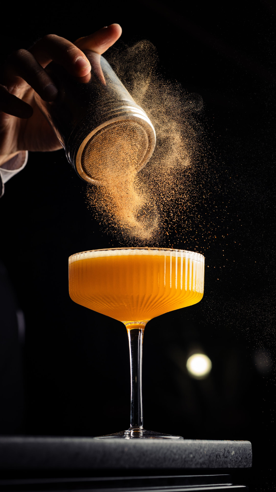 Bartender dusting spice over a coupe